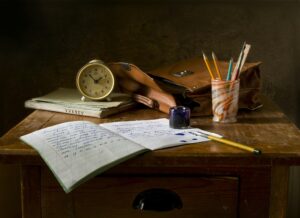 Study table with notebook, pens and clock.