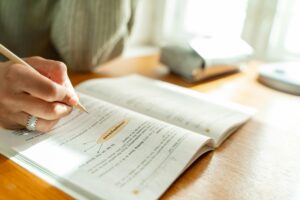 Student writing with pen on book